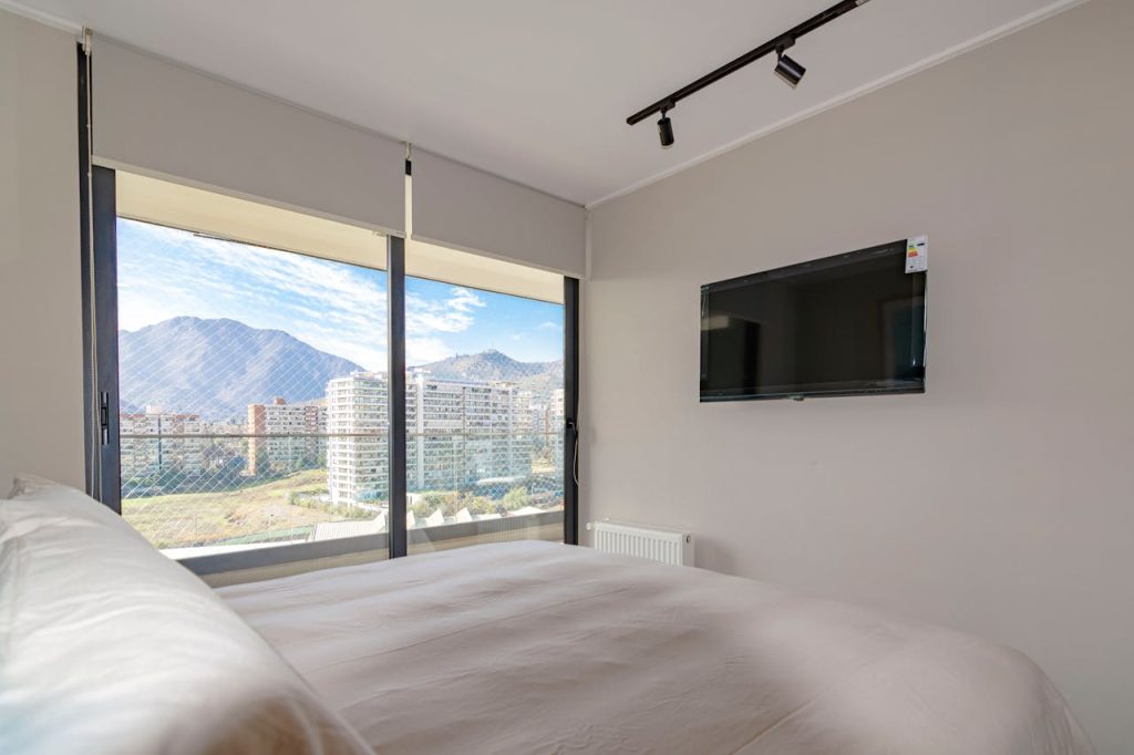Cozy bedroom interior with a stunning mountain view and wall-mounted TV.